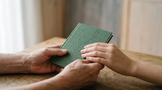 Gros plan sur des mains tenant un carnet d'épargne symbolisant la stratégie financière familiale